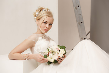 Image showing Bride in beautiful dress standing indoors in white studio interior like at home. Trendy wedding style shot. Young attractive caucasian model like a bride tender looking.