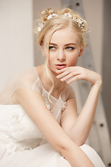 Image showing Bride in beautiful dress standing indoors in white studio interior like at home. Trendy wedding style shot. Young attractive caucasian model like a bride tender looking.
