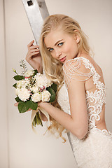 Image showing Bride in beautiful dress standing indoors in white studio interior like at home. Trendy wedding style shot. Young attractive caucasian model like a bride tender looking.