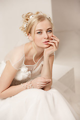 Image showing Bride in beautiful dress standing indoors in white studio interior like at home. Trendy wedding style shot. Young attractive caucasian model like a bride tender looking.