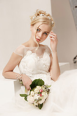 Image showing Bride in beautiful dress standing indoors in white studio interior like at home. Trendy wedding style shot. Young attractive caucasian model like a bride tender looking.