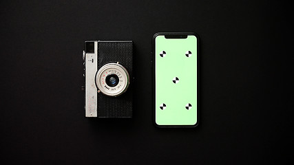 Image showing Old retro film camera and modern smartphone on black background