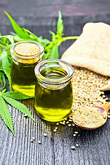 Image showing Oil hemp in two jars and flour in spoon on dark board