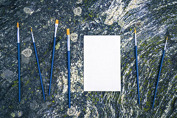 Image showing Paintbrushes and blank canvas on mossy stone background