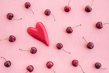 Image showing Cherries and red wooden heart on pink canvas