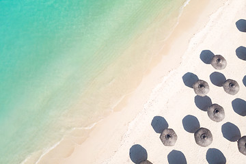 Image showing Aerial view of amazing tropical white sandy beach with palm leaves umbrellas and turquoise sea.