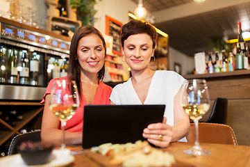 Image showing women with tablet pc at wine bar or restaurant