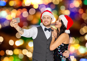 Image showing couple in santa hats taking selfie at christmas