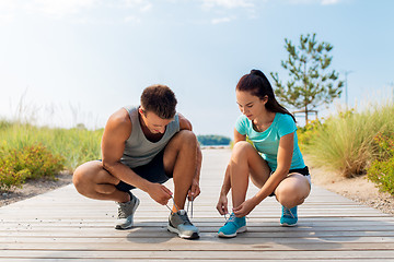 Image showing couple of joggers tying sneakers shoelaces