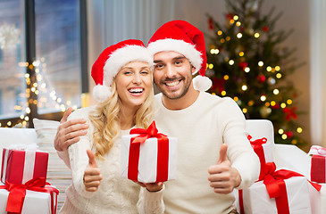 Image showing happy couple with christmas gifts and thumbs up