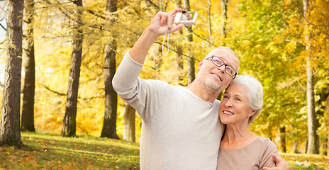 Image showing senior couple taking selfie in autumn park