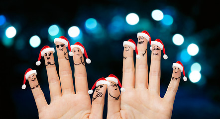 Image showing close up of ten fingers in santa hats over lights