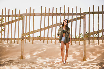 Image showing Beautiful young woman posing near a wood fence