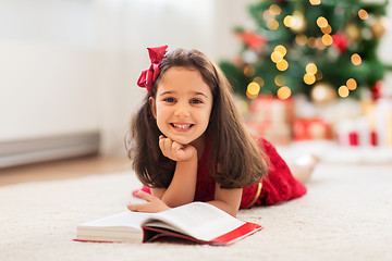 Image showing happy girl reading book at home on christmas