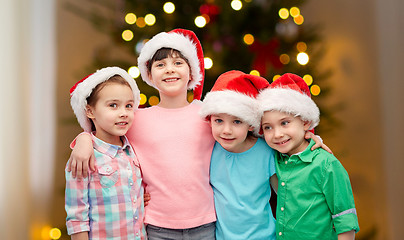 Image showing happy children in santa hats hugging on christmas