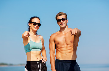 Image showing happy couple in sports clothes and shades on beach