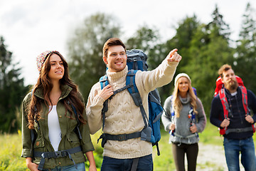 Image showing happy friends or travelers with backpacks hiking