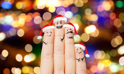 Image showing close up of four fingers in santa hats over lights