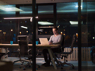 Image showing man working on laptop in dark office