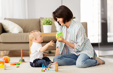 Image showing happy mother giving sippy cup to baby son at home