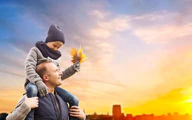 Image showing father carrying son with autumn leaves in city