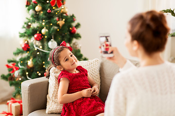 Image showing mother picturing daughter by phone on christmas