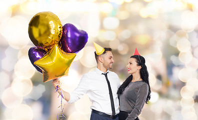 Image showing happy couple with party caps and balloons