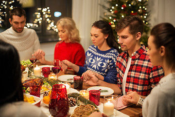 Image showing friends having home christmas dinner and praying