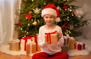 Image showing smiling girl in santa hat with christmas gift