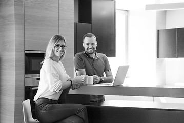 Image showing couple drinking coffee and using laptop at home