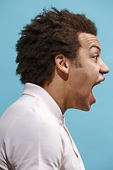 Image showing The young emotional angry man screaming on blue studio background