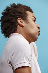 Image showing Beautiful male half-length portrait isolated on blue studio backgroud. The young emotional surprised man