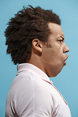 Image showing Beautiful male half-length portrait isolated on blue studio backgroud. The young emotional surprised man