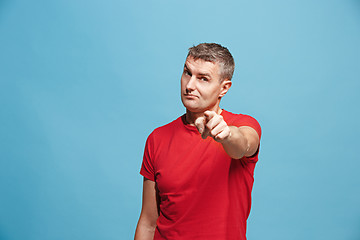 Image showing The serious business man point you and want you, half length closeup portrait on blue background.