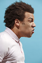 Image showing The young emotional angry man screaming on blue studio background