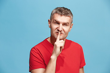 Image showing The young man whispering a secret behind her hand over blue background