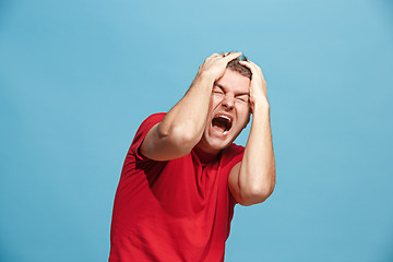 Image showing The young emotional angry man screaming on blue studio background