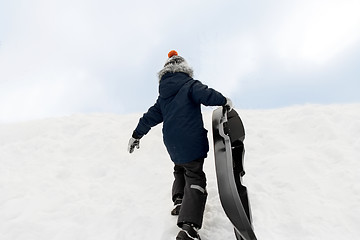 Image showing little boy with sled climbing snow hill in winter