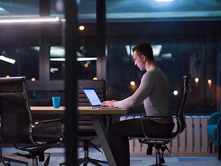 Image showing man working on laptop in dark office