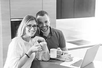 Image showing couple drinking coffee and using laptop at home