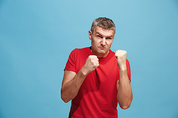 Image showing The young emotional angry man screaming on blue studio background