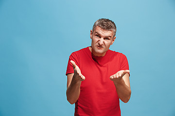 Image showing Beautiful male half-length portrait isolated on blue studio backgroud. The young emotional surprised man