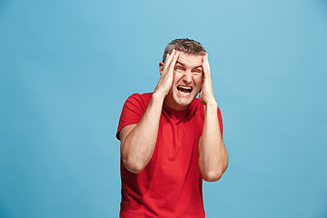 Image showing The young emotional angry man screaming on blue studio background