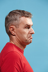 Image showing Suspiciont. Doubtful pensive man with thoughtful expression making choice against blue background