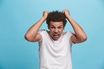 Image showing The young emotional angry man screaming on blue studio background