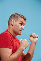 Image showing The young emotional angry man screaming on blue studio background