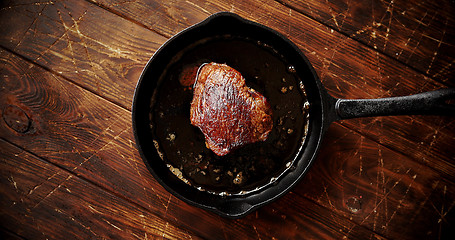 Image showing Piece of meat fried in oil on pan