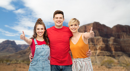 Image showing happy friends showing thumbs up and hugging