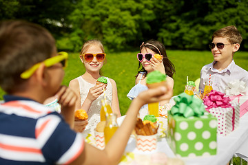 Image showing kids eating cupcakes on birthday party in summer