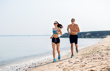 Image showing couple in sports clothes running along on beach